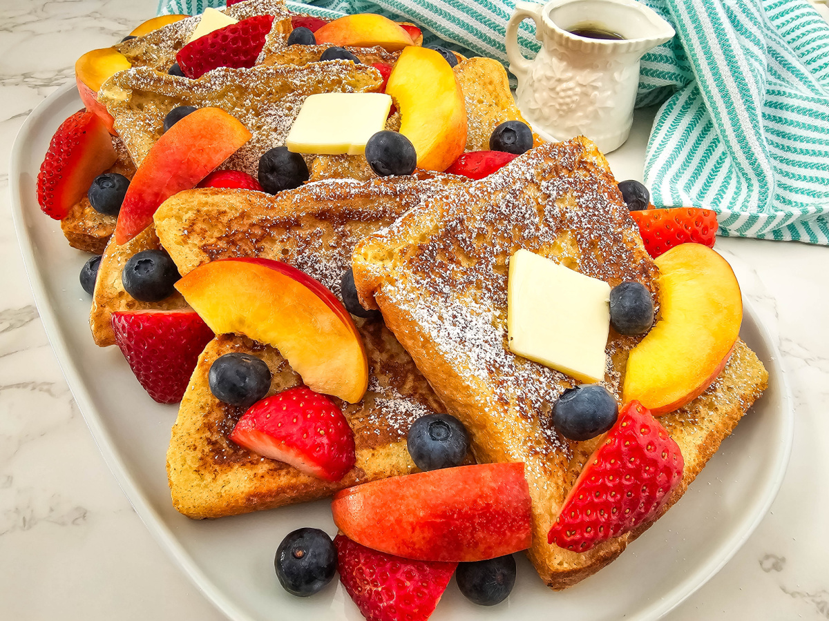 french toast with peaches and strawberries on platter