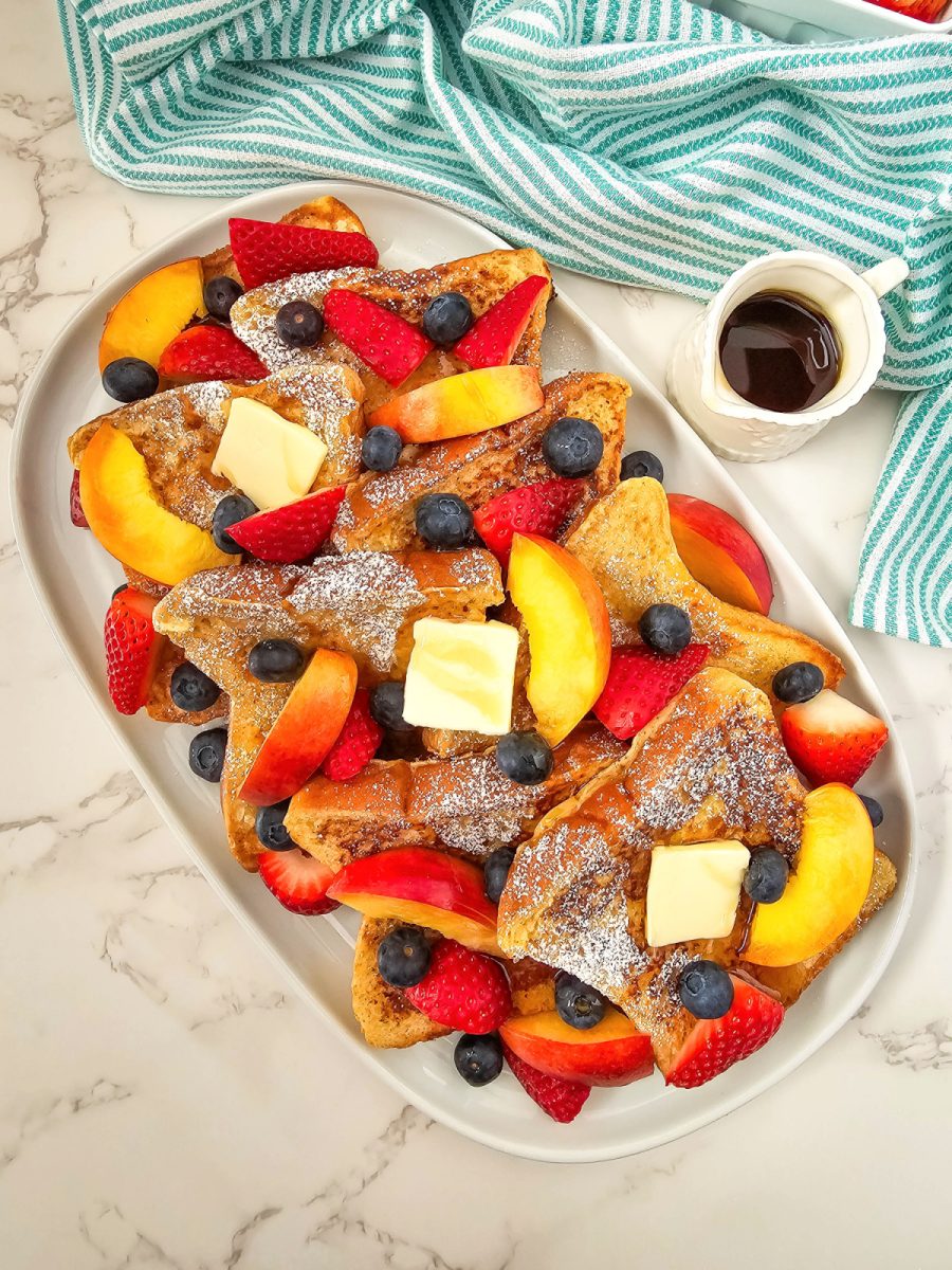 overhead shot of french toast with fresh fruit slices and syrup