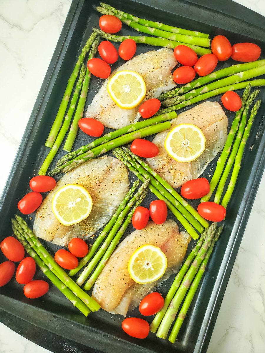 scatter tomatoes and asparagus around fish on pan