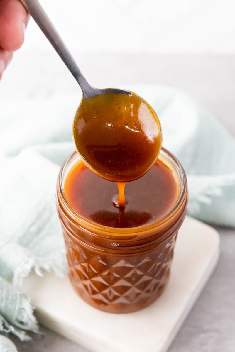 spoon with caramel sauce dipping out of jar