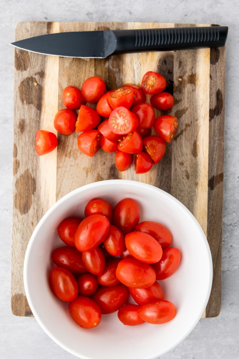 cutting tomatoes in half on cutting board