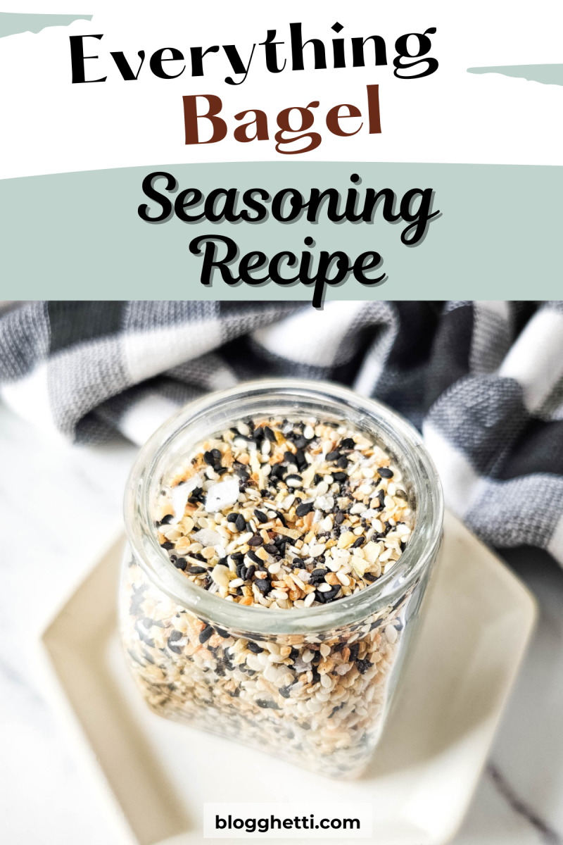 A jar filled with homemade everything bagel seasoning, made up of sesame seeds, poppy seeds, onion flakes, garlic powder, and other spices. The jar is sitting on a white plate with a black and white checkered cloth in the background.