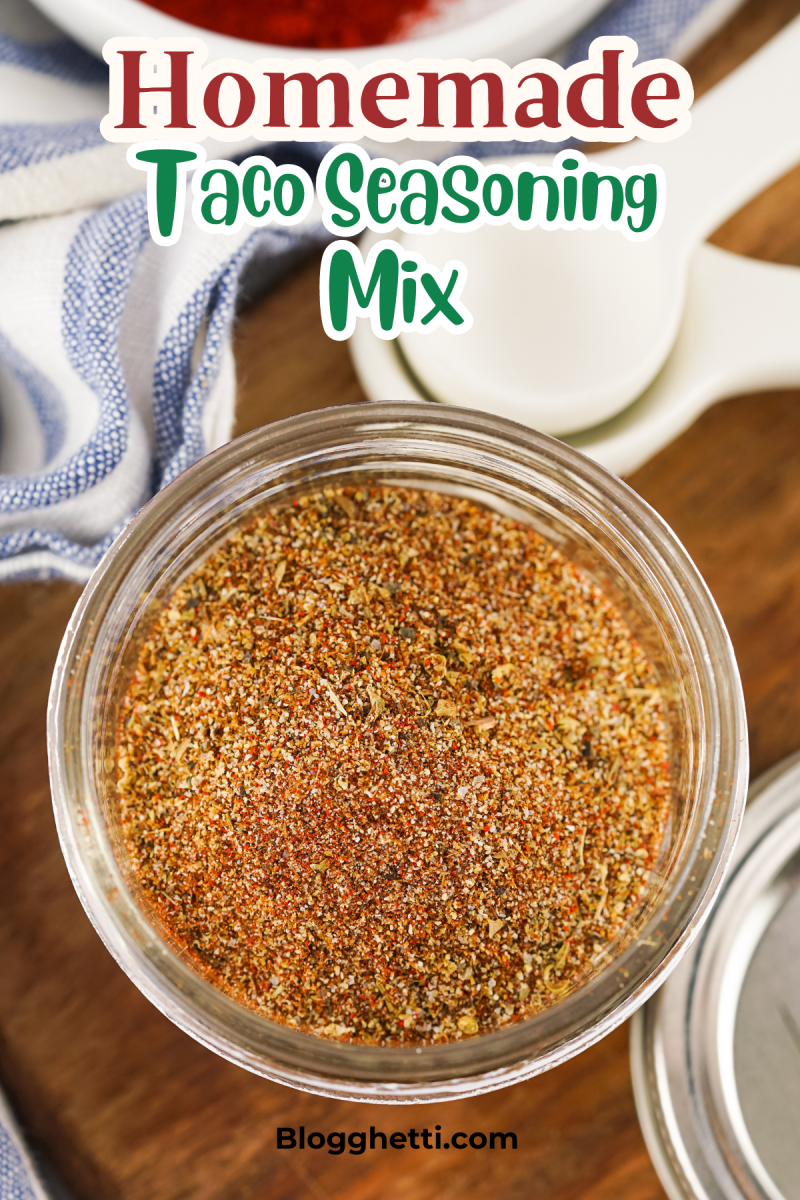 A jar of homemade taco seasoning mix. The seasoning is a vibrant red-brown color and appears to be made with a variety of spices.