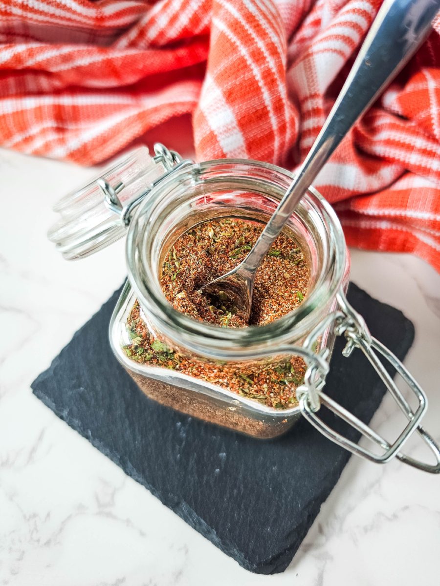 jar filled with a dark brown spice blend, topped with a metal spoon