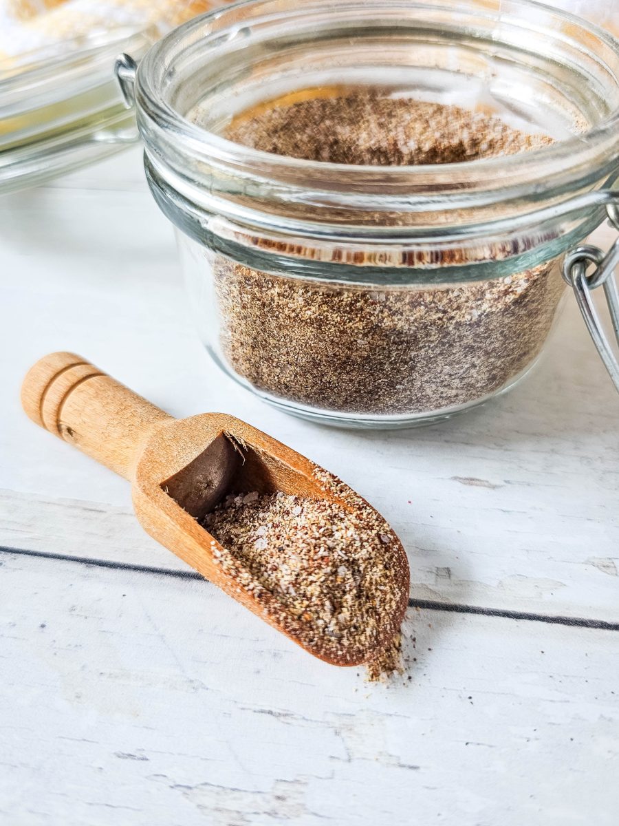 little wooden spoonful of spices with jar in the background