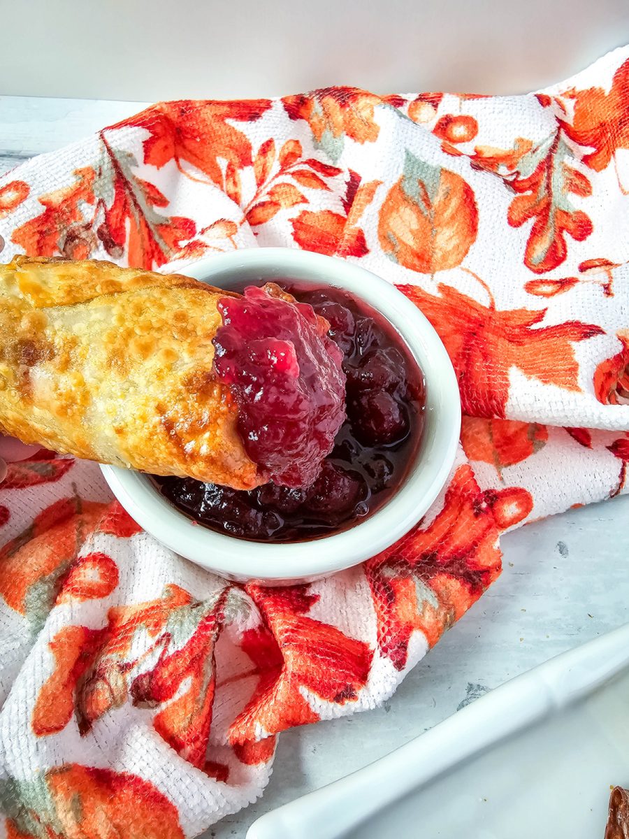 Air Fryer Thanksgiving Egg Roll dipped into cranberry sauce