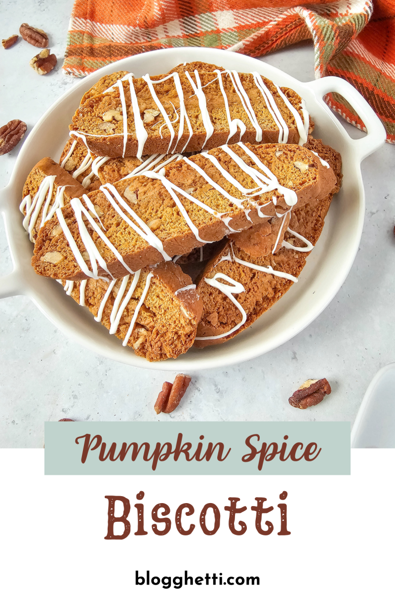 A plate of freshly baked pumpkin spice biscotti drizzled with white icing, served in a white dish. The biscotti are golden brown with a crunchy texture, studded with nuts, and neatly arranged. A warm orange plaid napkin is placed in the background, complementing the cozy fall vibe of the presentation. The text "Pumpkin Spice Biscotti" is written at the bottom