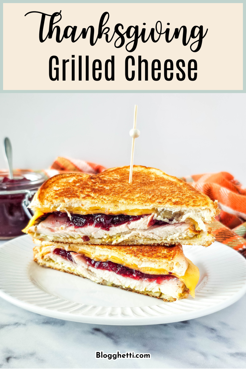 A delicious grilled cheese sandwich filled with turkey, and cranberry sauce on a white plate.