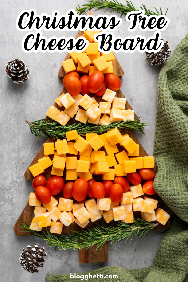 A Christmas tree-shaped cheese board with different types of cheese arranged in layers, resembling a tree. There are also cherry tomatoes and rosemary sprigs added for decoration