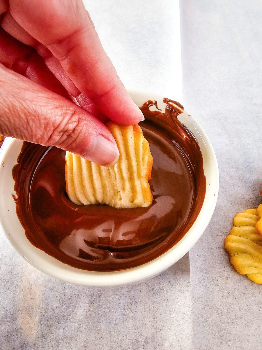 dipping a cookie into melted chocolate