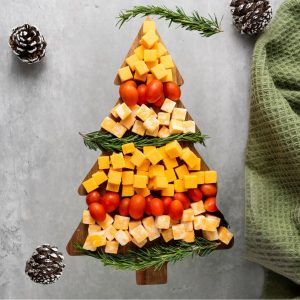 A Christmas tree-shaped cheese board with different types of cheese arranged in layers, resembling a tree. There are also cherry tomatoes and rosemary sprigs added for decoration