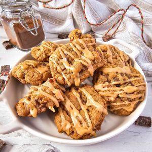 A close-up image of a plate of coffee chocolate chip cookies. The cookies are golden brown and topped with chocolate chips and a drizzle of coffee glaze.