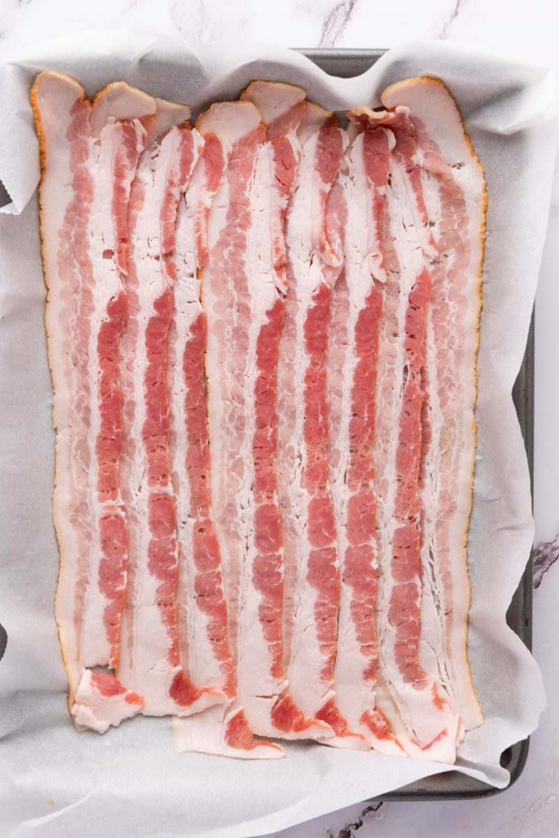 raw bacon on tray to bake