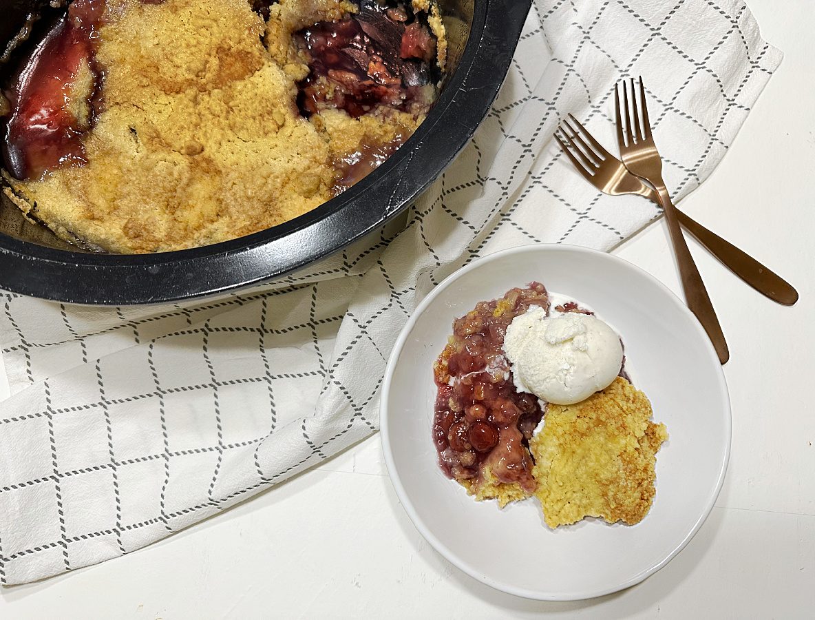 cherry pineapple dump cake on white plate with slow cooker in the background