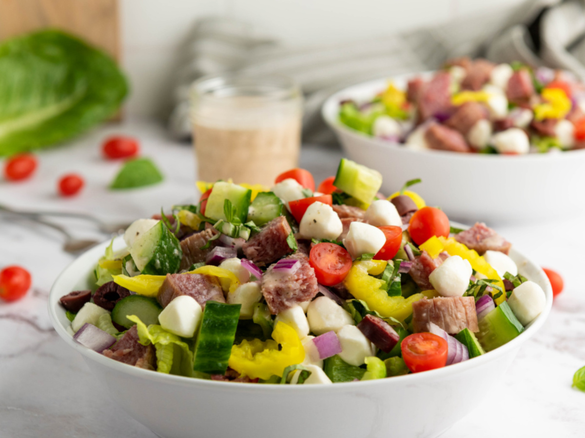 close up tossed salad with dressing jar