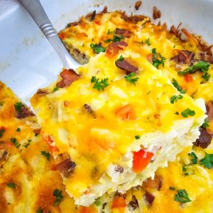 close up of a silver spatula with a serving of hashbrown casserole on it.