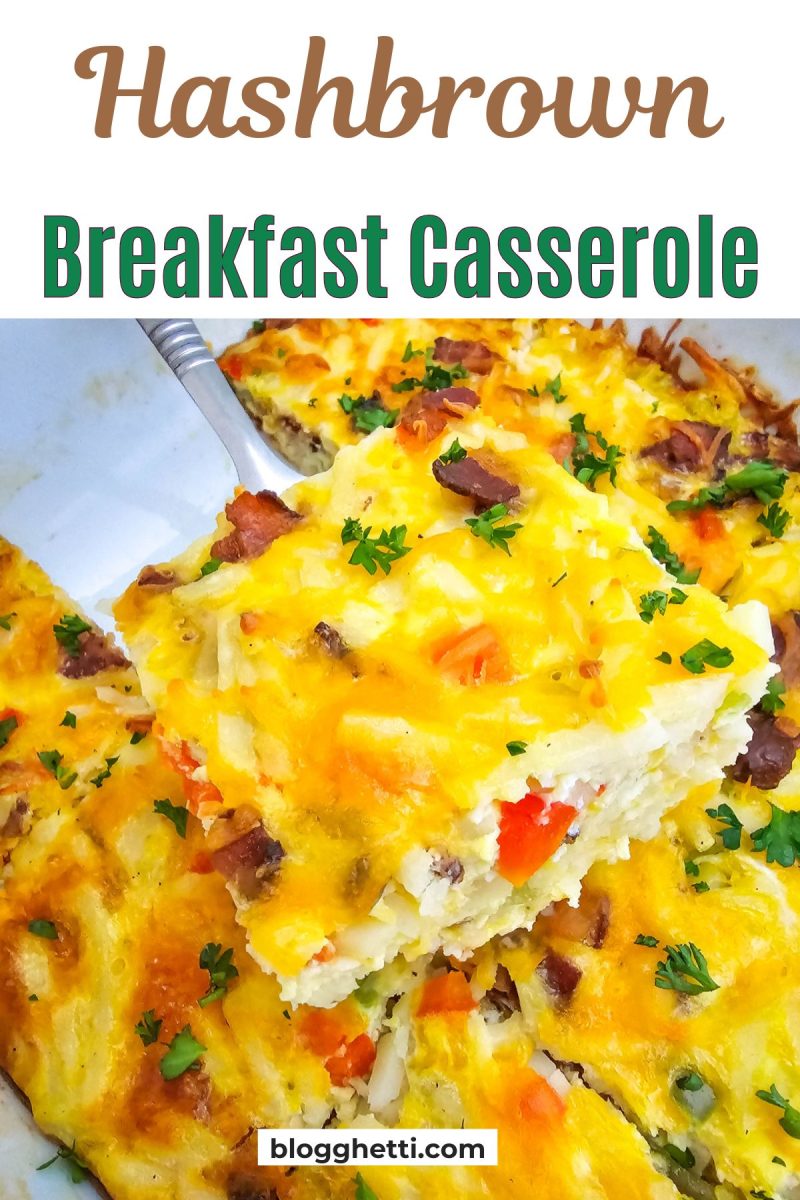 A slice of golden brown hashbrown breakfast casserole is lifted with a silver spatula, revealing layers of shredded potatoes, egg, melted cheddar cheese, red and green bell peppers, and bacon, garnished with fresh green parsley, against a background of the remaining casserole in a white dish.