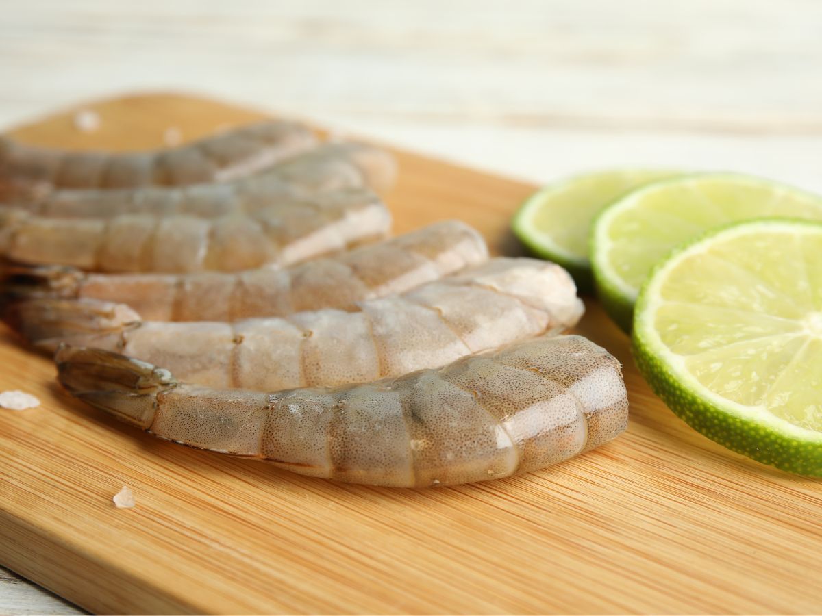 raw shrimp and lime slices on cutting board