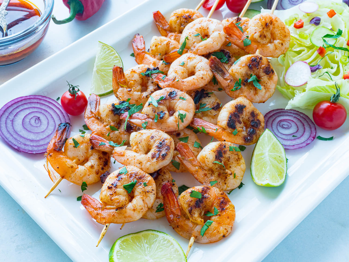shrimp skewers on white platter with garnishes