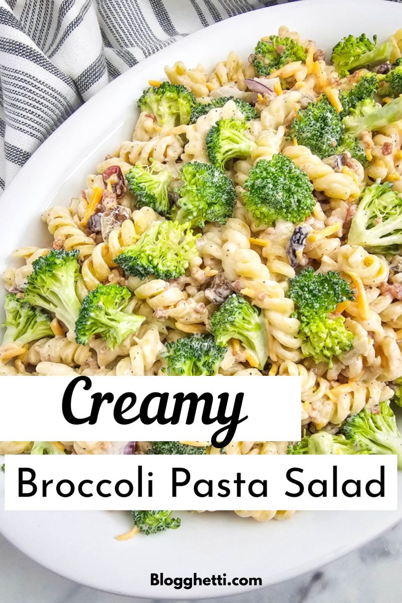 A white oval platter filled with creamy broccoli pasta salad, featuring rotini pasta and broccoli florets, with the words "Creamy Broccoli Pasta Salad"