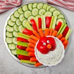 A full view of the assembled vegetable tray shaped like a turkey, with a white and red striped towel visible in the background.
