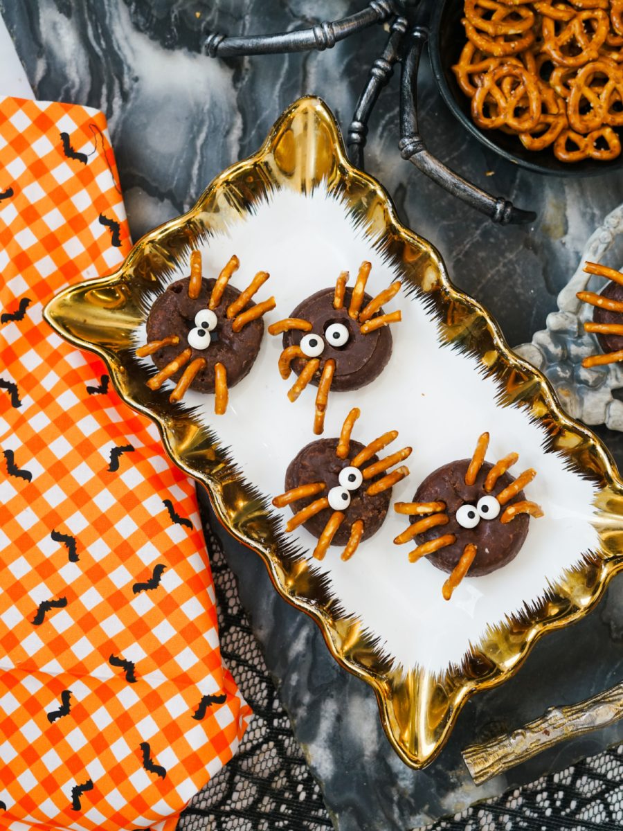 Top-down shot of four assembled mini chocolate spider donuts arranged on a white and gold platter, ready for a Halloween party.