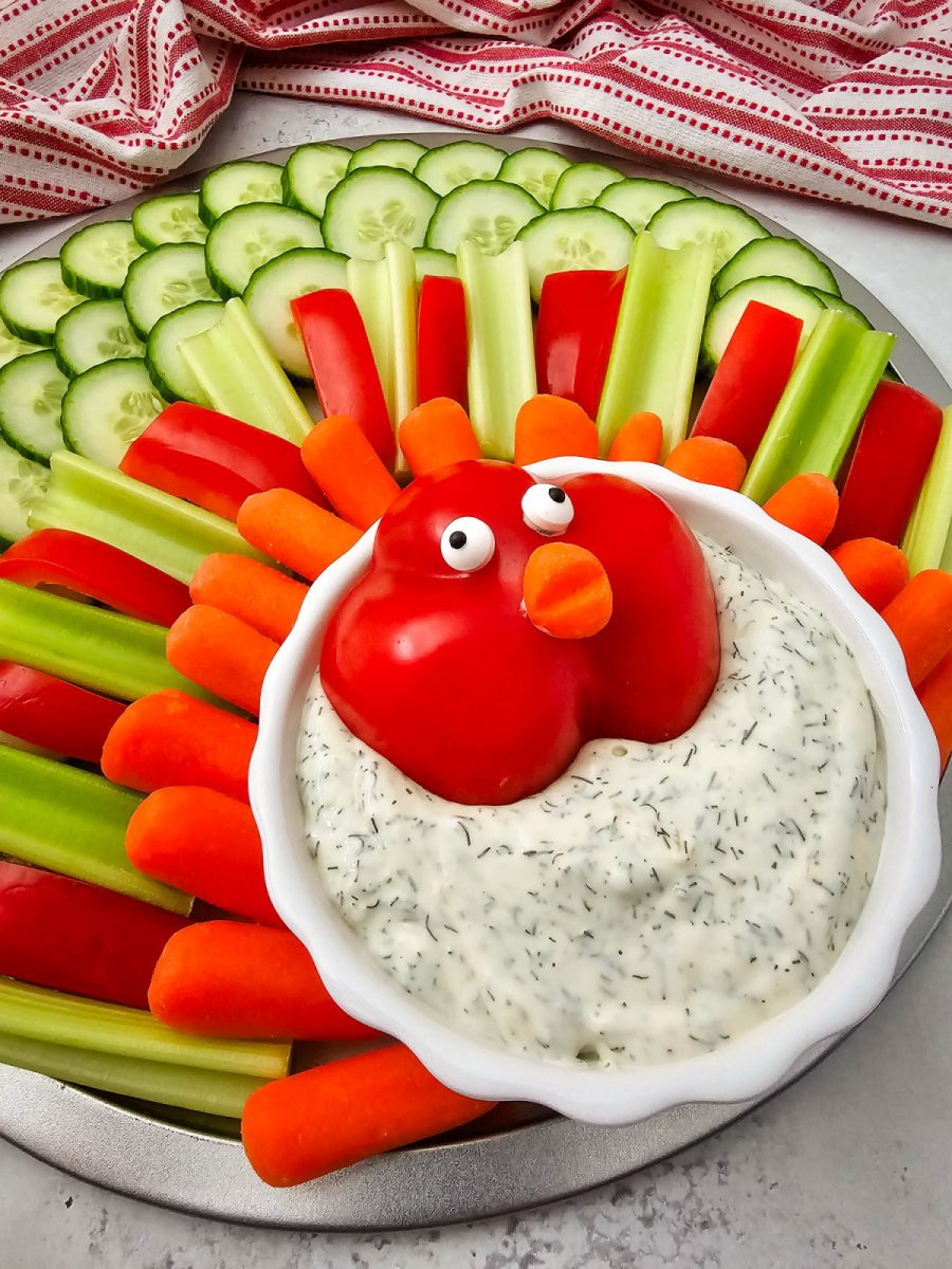 A close-up, slightly angled view of the finished turkey-shaped vegetable platter, focusing on the red bell pepper head with candy eyes and carrot beak.