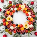 Overhead, high-quality feature image of the Simple Christmas Wreath Charcuterie Board, fully garnished with rosemary and holiday ornaments, showcasing the circular pattern.