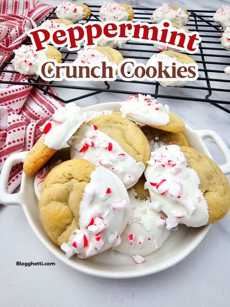 Finished cookies piled in a white serving dish next to a cooling rack, all half-dipped in white chocolate and covered with crushed peppermint.