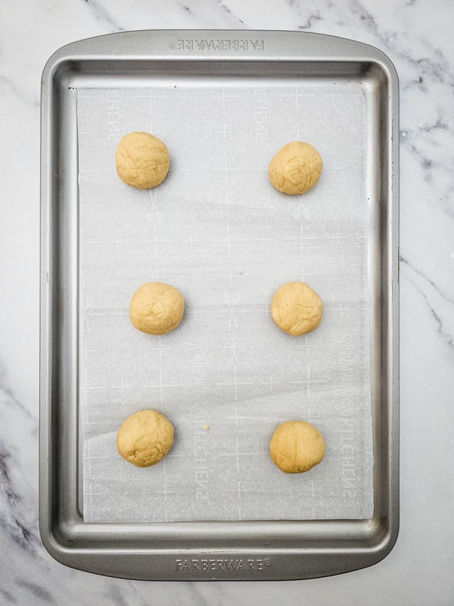 Raw Peppermint Crunch Cookies dough rolled into uniform balls and placed on a parchment-lined baking sheet, ready to be baked to golden perfection.