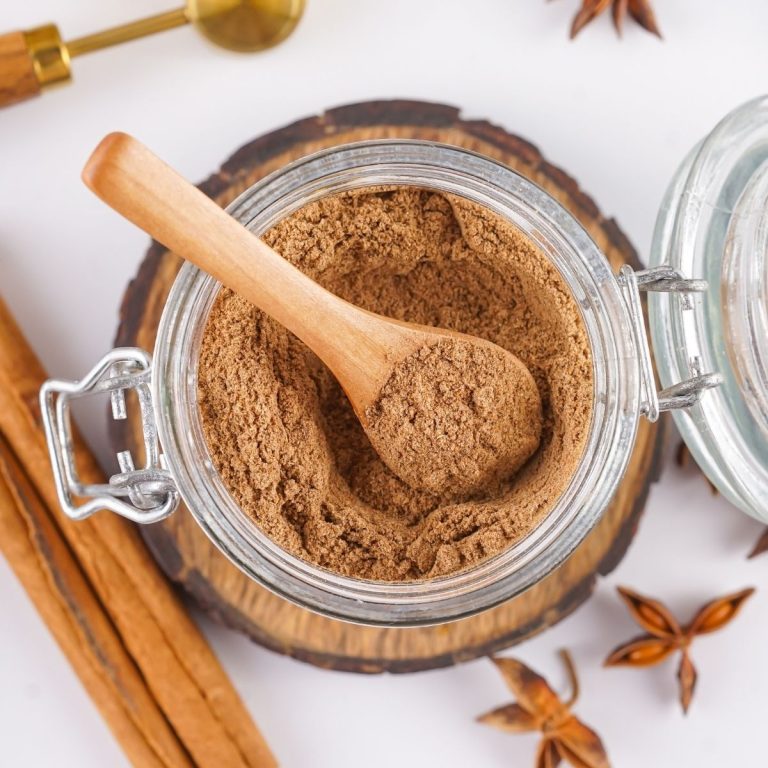 mix.jpg An overhead view of a glass jar containing a powdered chai spice mix with a wooden spoon tucked inside and cinnamon sticks on the side.