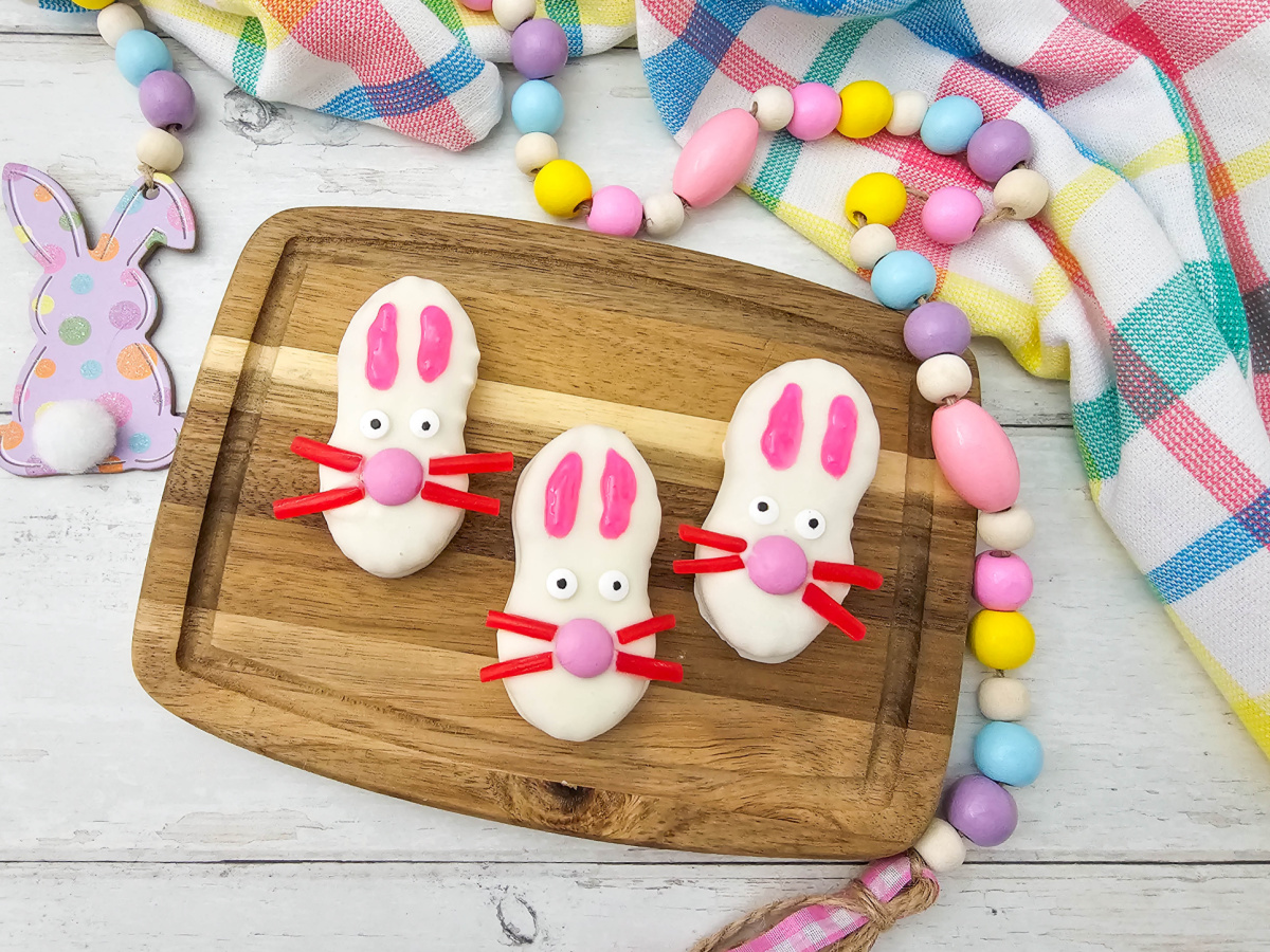 A wide top-down perspective of the decorated Easter bunny cookies showcasing the festive table setting, including a purple bunny ornament and pastel decorations on a light wood background.