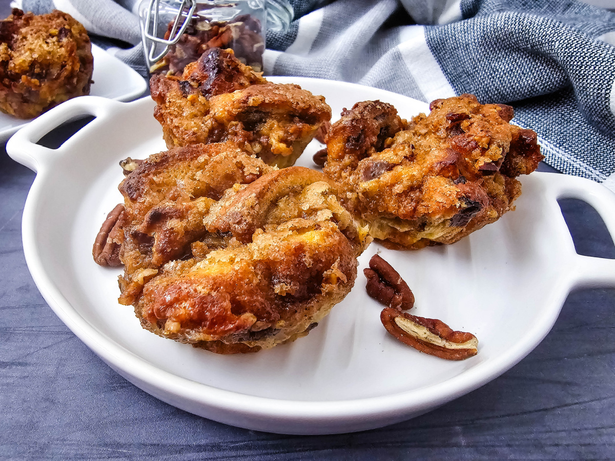 Close up view of crispy cinnamon raisin French toast muffins with a pecan crumble topping on a white plate.