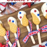 A festive Pinterest pin graphic featuring patriotic nutter butter cookie pops. The upper half shows a clean white text box displaying the recipe title, while the lower background shows the decorated cookies on a wooden tray with holiday star decorations.