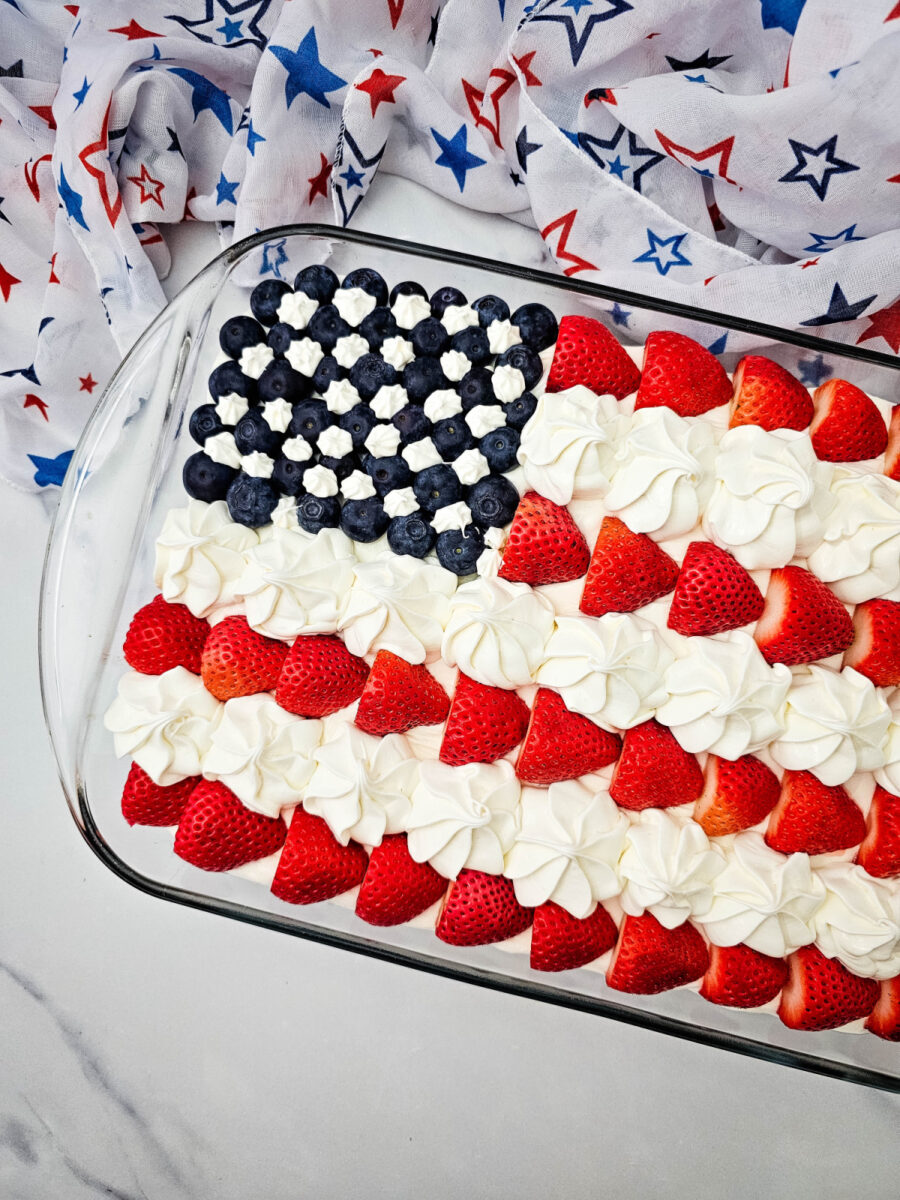 Close-up of strawberries, blueberries, and frosting stars on a holiday cake