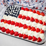 American Flag Cake Recipe decorated with strawberries, blueberries, and frosting stars