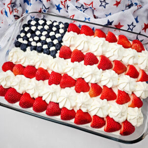 American Flag Cake Recipe decorated with strawberries, blueberries, and frosting stars