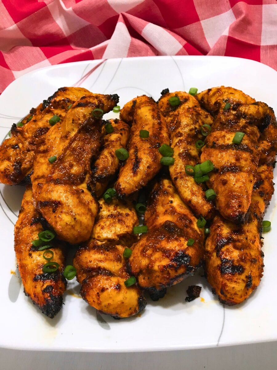 Grilled Nashville Hot Chicken Tenders served on a white platter and garnished with sliced green onions.