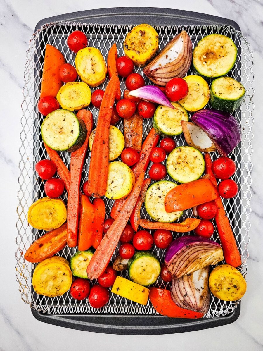 Marinated summer vegetables arranged on a grill pan before cooking.