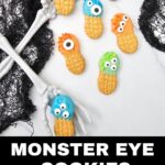 Colorful monster eye cookies decorated with candy melts, sprinkles, and assorted candy eyes are arranged with skeleton hands and black lace. Text reads, “Monster Eye Cookies: Fun Halloween Party Treat.”