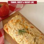 Whole loaf garnished with rosemary on a wooden board beside red apples. Text reads “Savory Apple Cheddar Quick Bread,” “Tender, Cheesy and Biscuit-Like,” and “Blogghetti.com.”