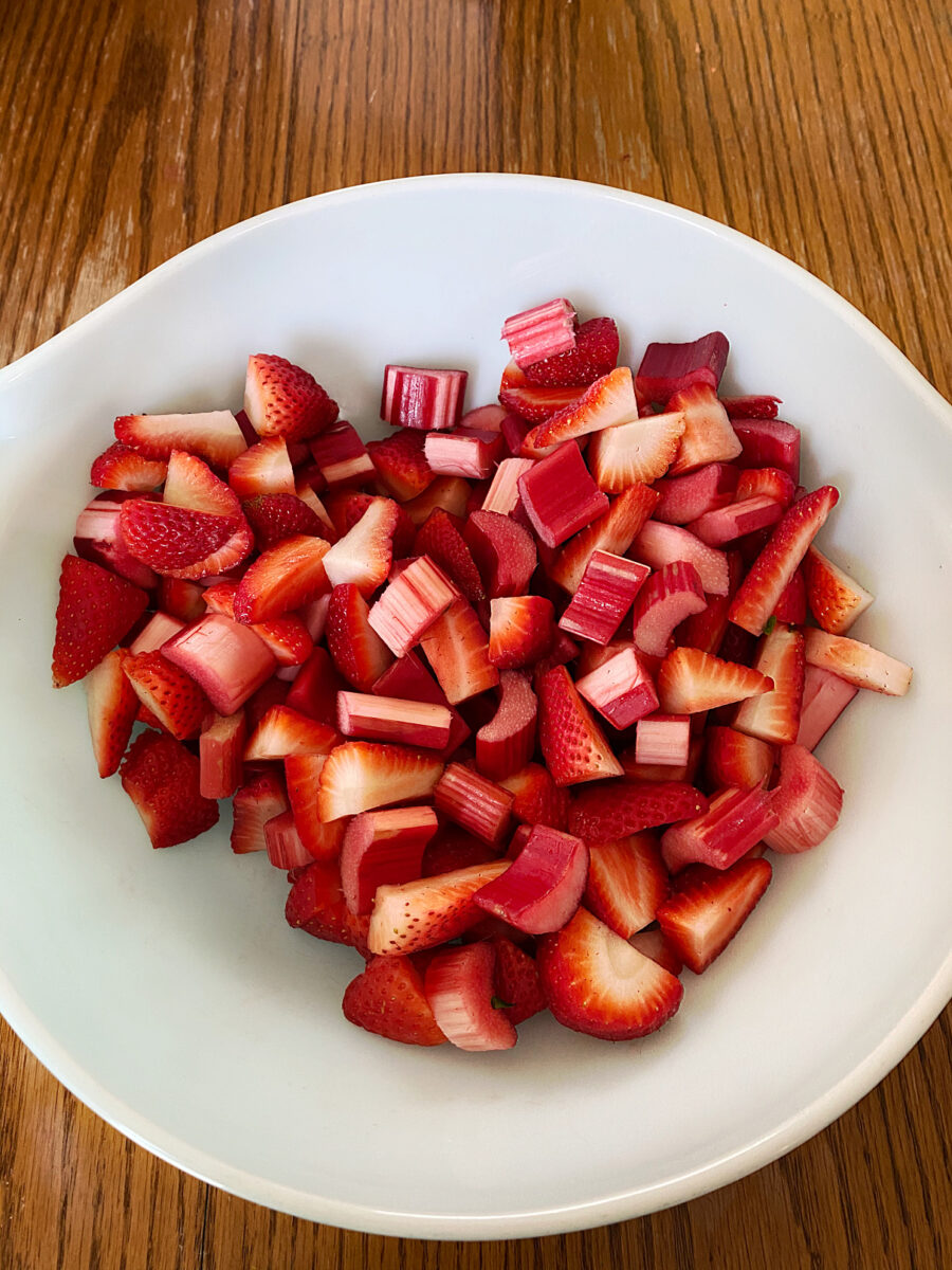Chopped strawberries and rhubarb in a white bowl, ready to be mixed with the remaining filling ingredients.